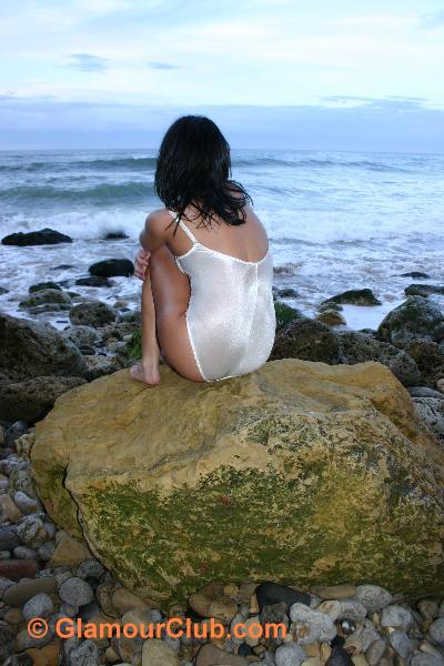 Jaki Leigh in white bodysuit on rock looking out to sea